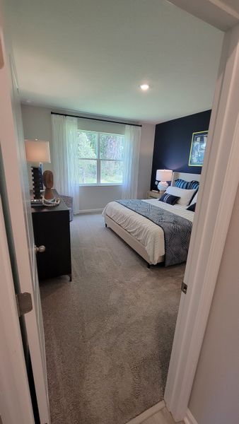 Cozy bedroom with plush carpet, a large window, and dark accent wall, featuring a stylish bed and elegant decor. Cozy bedroom with plush carpet, a large window, and dark accent wall, featuring a stylish bed and elegant decor.