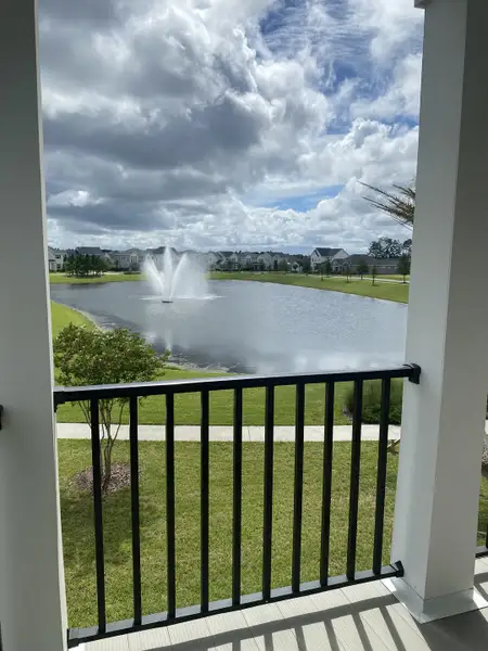 A serene view of a fountain and pond from a balcony, under a dramatic cloudy sky in Jacksonville, FL.