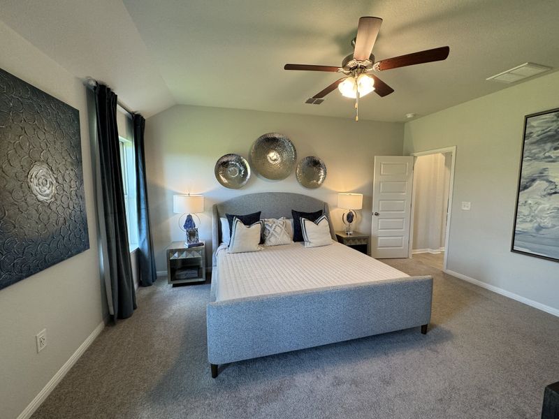 A cozy bedroom featuring a plush gray bed, decorative wall plates, and stylish lighting fixtures. A cozy bedroom featuring a plush gray bed, decorative wall plates, and stylish lighting fixtures.