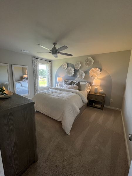 A cozy bedroom featuring plush bedding, decorative wall art, and soft carpet, with ample natural light filtering through. A cozy bedroom featuring plush bedding, decorative wall art, and soft carpet, with ample natural light filtering through.