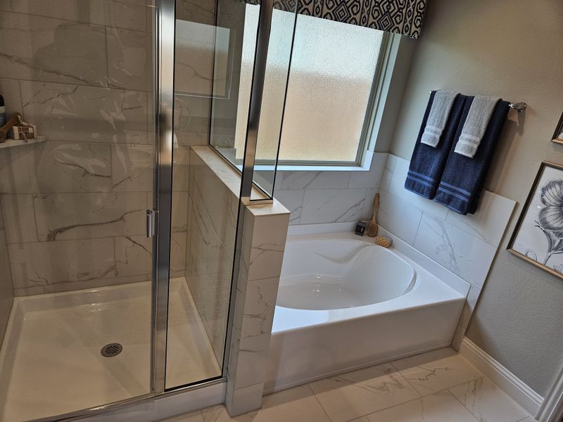 A modern bathroom featuring a glass shower, marble-tiled tub, and elegant decor with natural light. A modern bathroom featuring a glass shower, marble-tiled tub, and elegant decor with natural light.