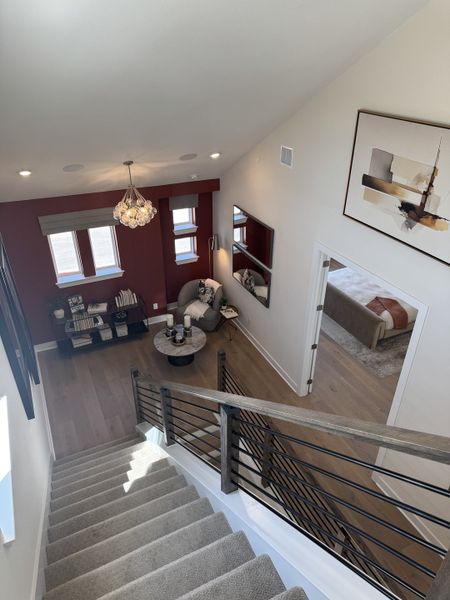 A cozy living space with plush seating, modern art, and elegant lighting viewed from a staircase.
