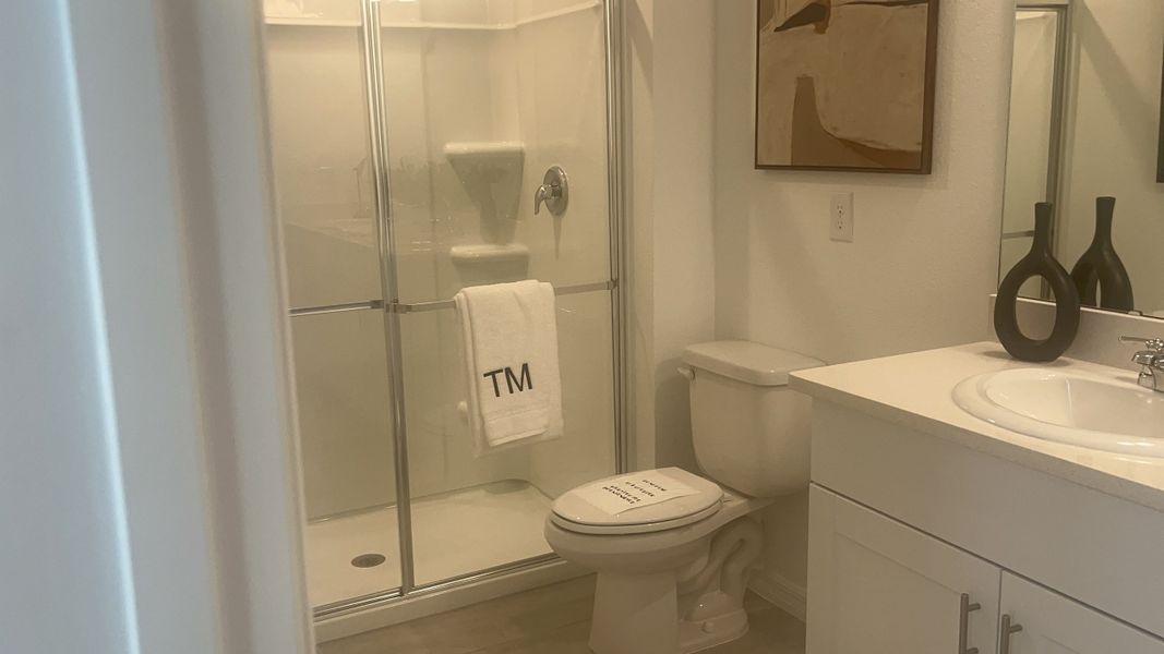 A modern bathroom featuring a glass-enclosed shower, sleek vanity, and elegant wall art.