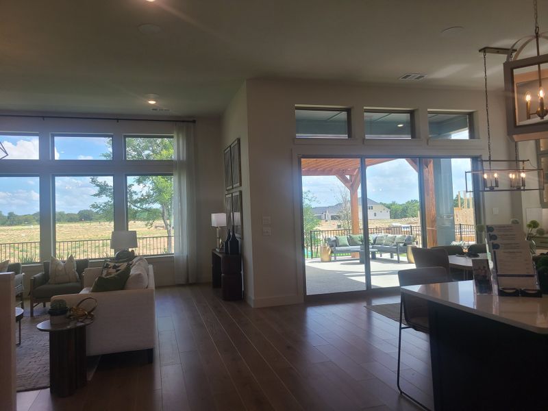 A bright, open-concept living area with expansive windows, wood flooring, and a view of the patio and outdoors. A bright, open-concept living area with expansive windows, wood flooring, and a view of the patio and outdoors.