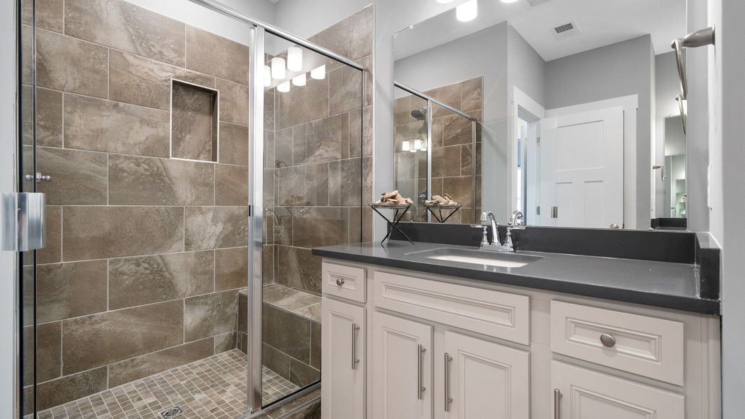 Primary bathroom with white cabinetry vanity with granite countertops and walk-in tiled shower in Fountain Inn, SC