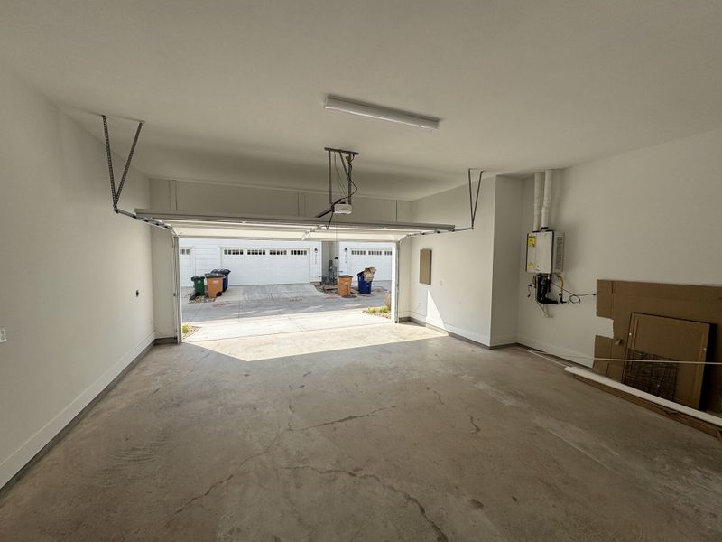 A spacious, clean garage with an open door, showcasing a neat driveway and ample storage potential. A spacious, clean garage with an open door, showcasing a neat driveway and ample storage potential.