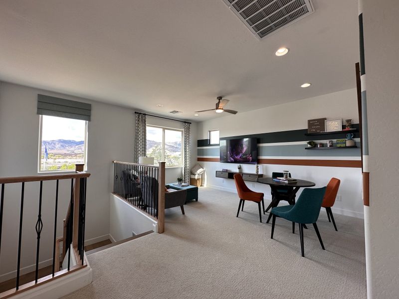 A modern loft area with cozy seating, striped accent wall, and natural light through large windows with mountain views.