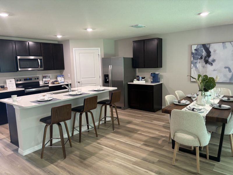 A modern kitchen with sleek dark cabinets, stainless steel appliances, and a cozy dining area featuring a stylish wooden table. A modern kitchen with sleek dark cabinets, stainless steel appliances, and a cozy dining area featuring a stylish wooden table.