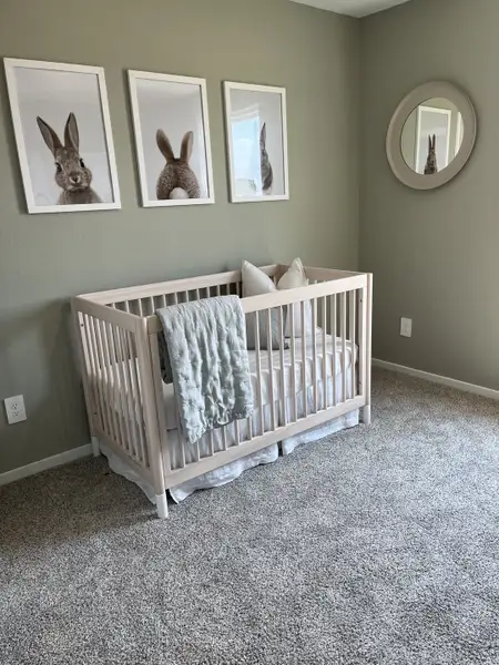 A cozy nursery with a light wood crib, soft carpet, and whimsical bunny art for a serene, playful atmosphere.
