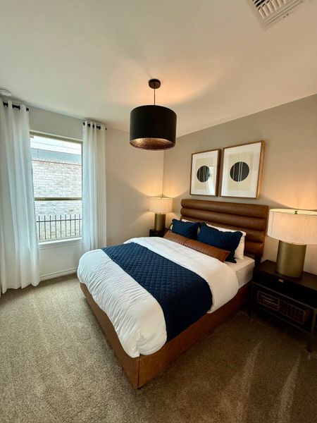A cozy bedroom with a padded headboard, modern pendant light, and elegant decor featuring neutral tones and navy accents. A cozy bedroom with a padded headboard, modern pendant light, and elegant decor featuring neutral tones and navy accents.