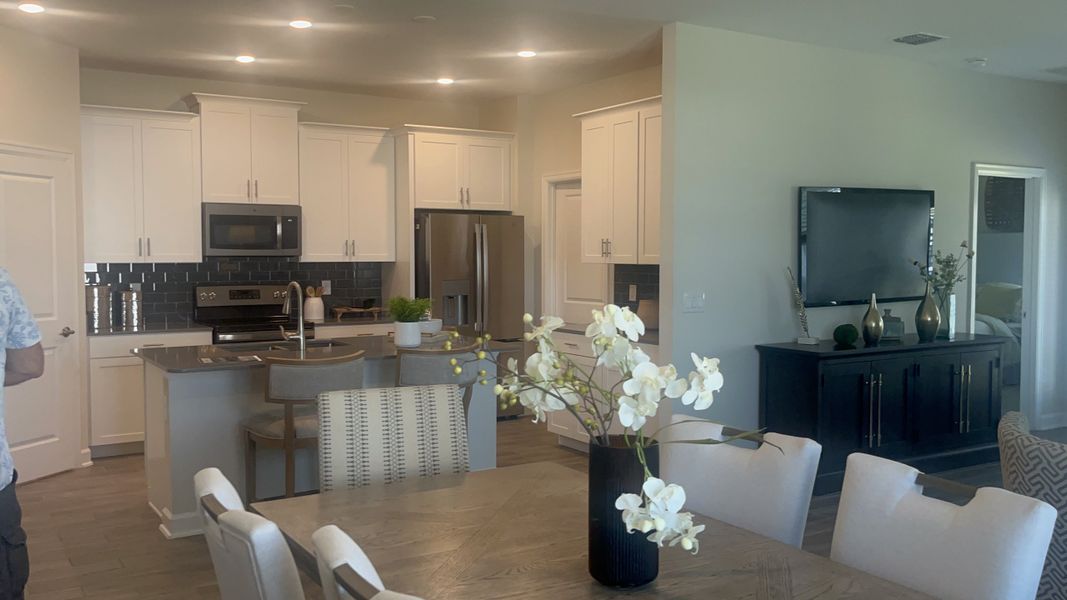 A modern kitchen and dining area featuring sleek cabinets, stainless appliances, and a stylish floral arrangement.