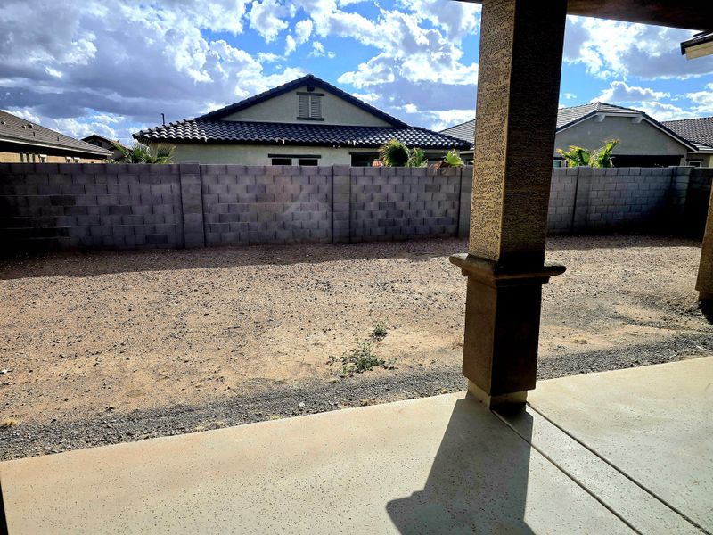 A spacious backyard with a covered patio and privacy wall at North Shore at Escalante by Fulton Homes (Surprise, AZ).