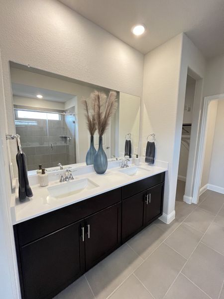 A modern bathroom with dual sinks, sleek dark vanity, and elegant tile flooring. A modern bathroom with dual sinks, sleek dark vanity, and elegant tile flooring.