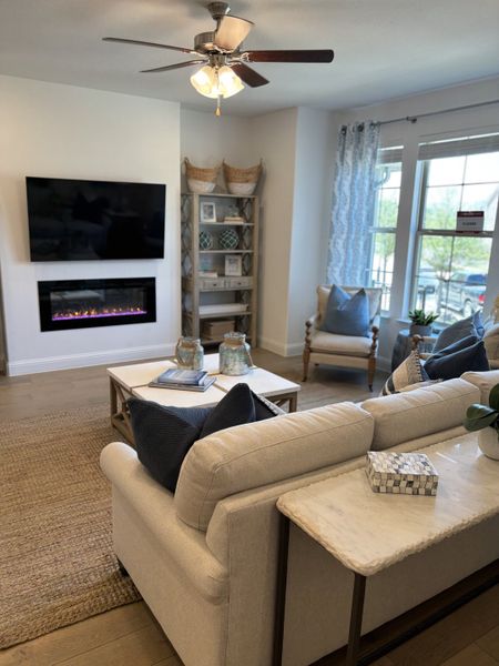 A cozy living room featuring a modern fireplace, plush seating, and elegant decor with a soft, neutral palette.