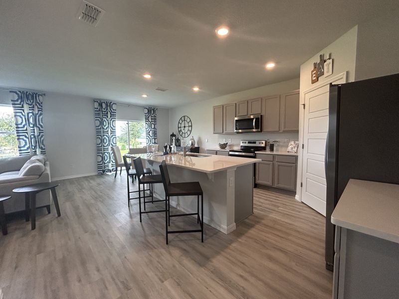An open-concept kitchen and living area with modern cabinetry, island seating, and large windows.