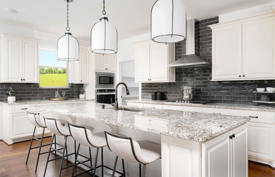 Designer fixtures and kitchen island seating in Palmary floor plan at Del Webb Fulshear
