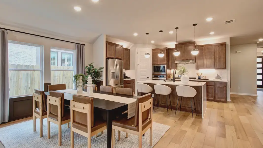 Sunflower Ridge kitchen features high-end wooden cabinetry and chic lighting. Large windows invite natural light.