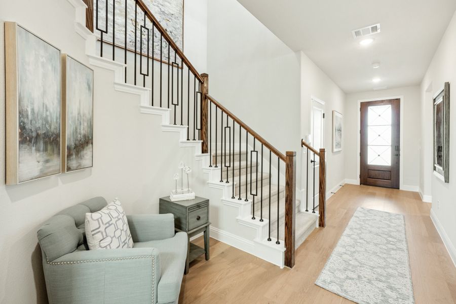 Bright entryway with staircase featuring wood and iron railing, hardwood floors, and front door with glass panels Bright entryway with staircase featuring wood and iron railing, hardwood floors, and front door with glass panels