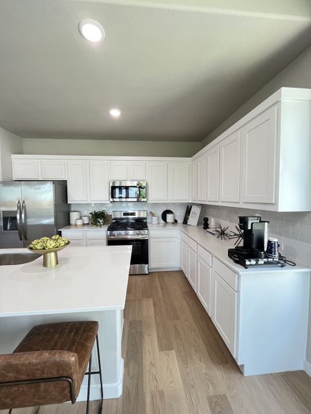 A modern kitchen featuring sleek white cabinets, stainless appliances, and a spacious island with bar seating. A modern kitchen featuring sleek white cabinets, stainless appliances, and a spacious island with bar seating.
