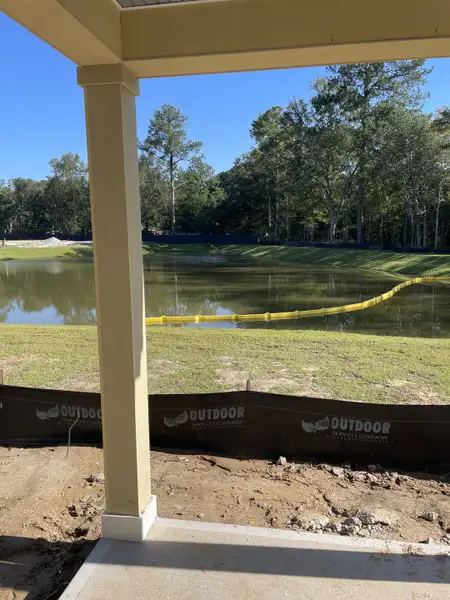 Serene pond view from a porch in Founders Corner by D.R. Horton, Lincolnville, SC, with lush greenery in the background.