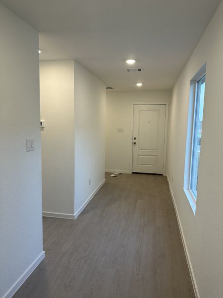 A modern entryway with sleek grey flooring, bright white walls, and recessed lighting creating a welcoming atmosphere.