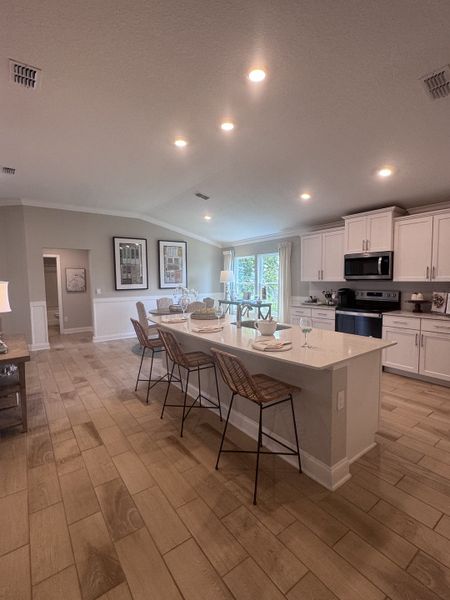 An inviting kitchen with a large island, bar stools, wooden floors, and ample natural light, creating a warm, open space.
