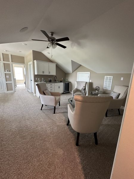 A cozy sitting area with plush armchairs, beige carpeting, and a ceiling fan, perfect for relaxation. A cozy sitting area with plush armchairs, beige carpeting, and a ceiling fan, perfect for relaxation.