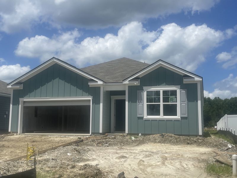 A charming blue home with white shutters and a two-car garage in The Oaks at Center Station by D.R. Horton (Hollywood, SC).