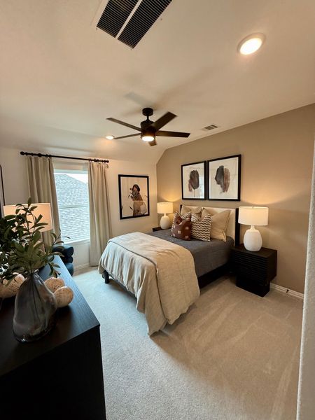 A cozy bedroom with neutral tones, modern bed, decorative pillows, and framed art, creating a warm and inviting space.