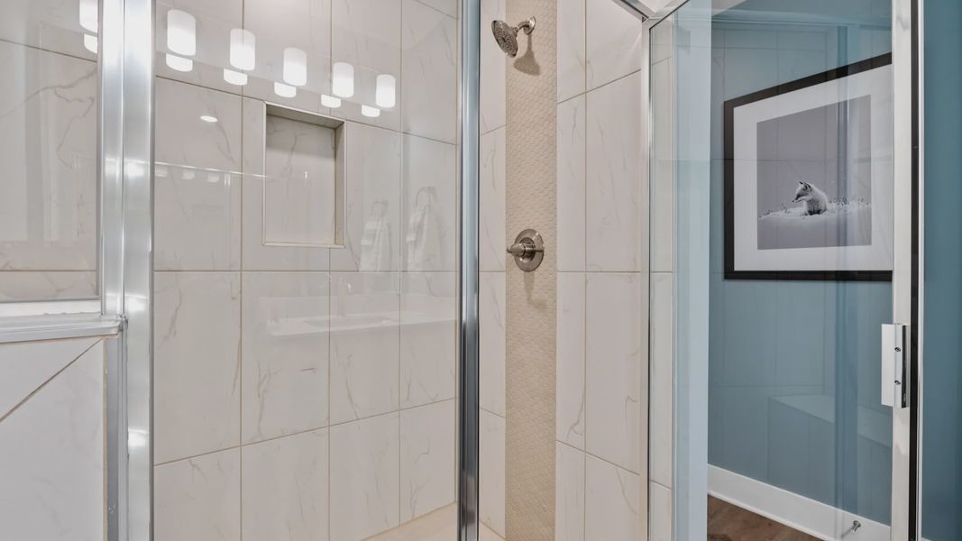 Marble tiled walk-in shower in primary bathroom in two story townhome at Saluda Crossing by DRB Homes in Piedmont, SC
