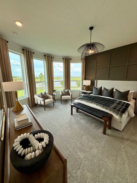 A serene bedroom with large windows, plush carpeting, elegant seating, and a stylish pendant light.