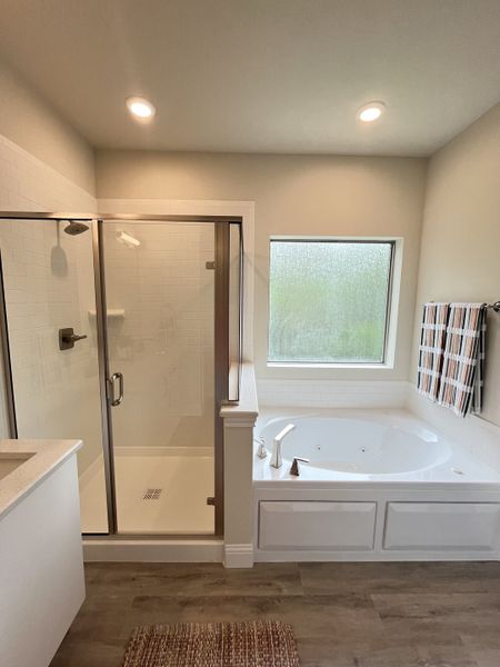 A modern bathroom with a glass shower, soaking tub, and large window, offering a serene retreat.