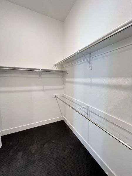 A spacious walk-in closet with sleek metal shelving and soft carpet flooring. A spacious walk-in closet with sleek metal shelving and soft carpet flooring.