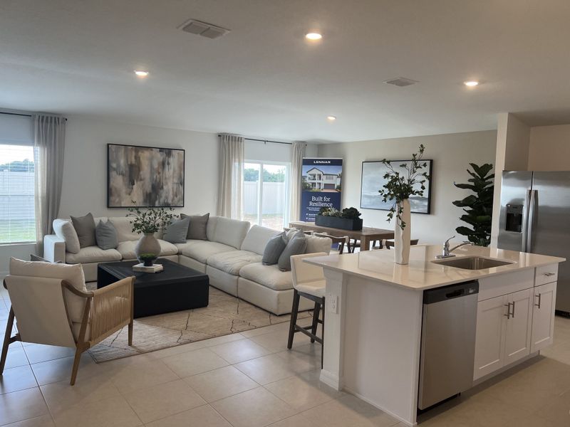 An elegant open-plan living area with a cozy sectional, sleek kitchen island, and modern decor.