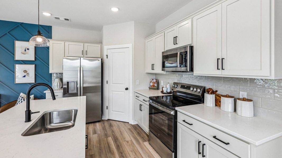 View of kitchen with quartz countertops, tile backsplash, and pendant lighting