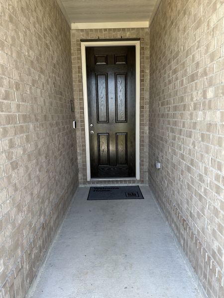 A welcoming entrance with a classic black door and serene brick walls.