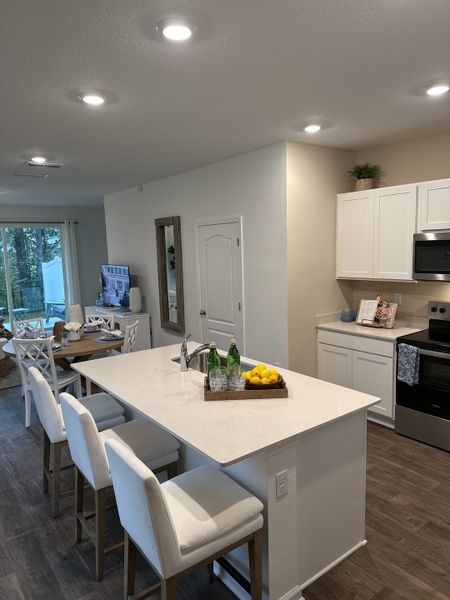 Modern kitchen with a sleek island, white cabinetry, and dining area, offering an inviting, open-concept space. Modern kitchen with a sleek island, white cabinetry, and dining area, offering an inviting, open-concept space.