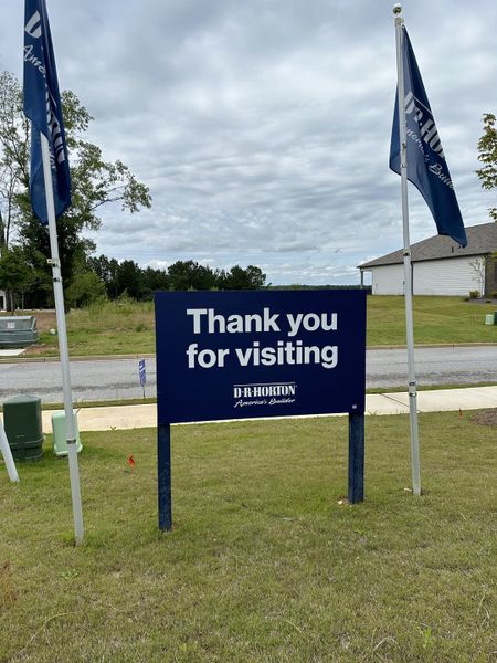 Visitor signage at Oaks at Cedar Grove by D.R. Horton, surrounded by greenery in Fairburn, GA.