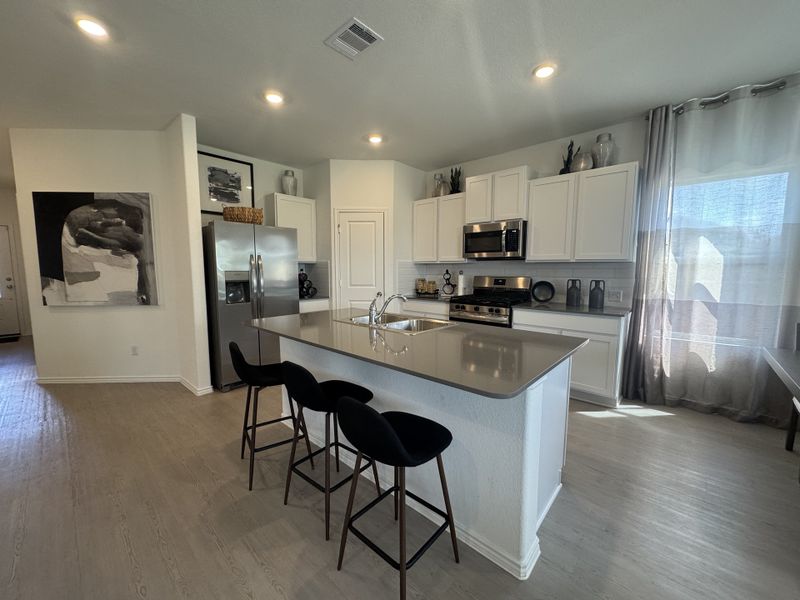 A modern kitchen with sleek white cabinets, stainless steel appliances, and a large island with stylish seating.