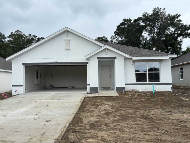 A modern white home with a spacious garage and simple landscaping in Autumn Glen by D.R. Horton (Belleview, FL).