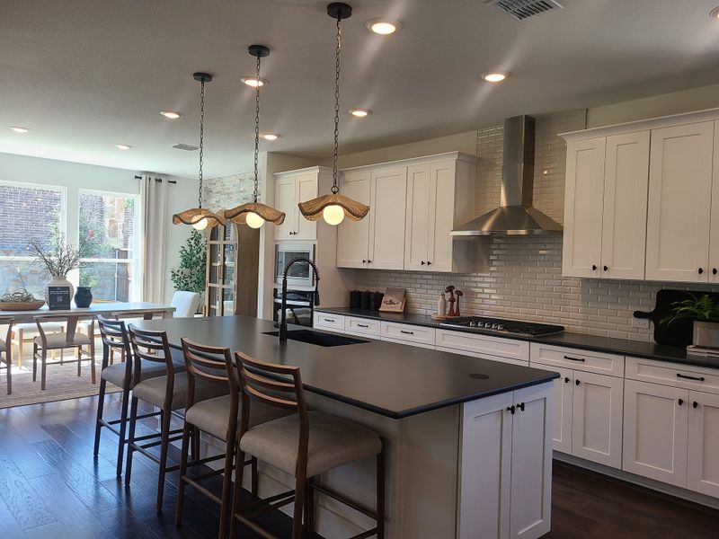 A modern kitchen with a large island, stylish pendant lights, and white cabinetry. Bright and open with ample natural light. A modern kitchen with a large island, stylish pendant lights, and white cabinetry. Bright and open with ample natural light.