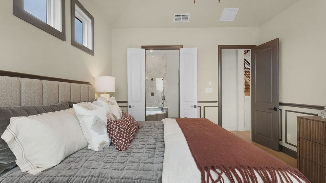 Owner’s suite with abundant natural light, woodwork details, and warm-toned flooring for a refined feel.