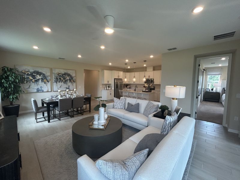 A spacious living area with an open layout, featuring a cozy sectional, stylish dining set, and modern kitchen. A spacious living area with an open layout, featuring a cozy sectional, stylish dining set, and modern kitchen.