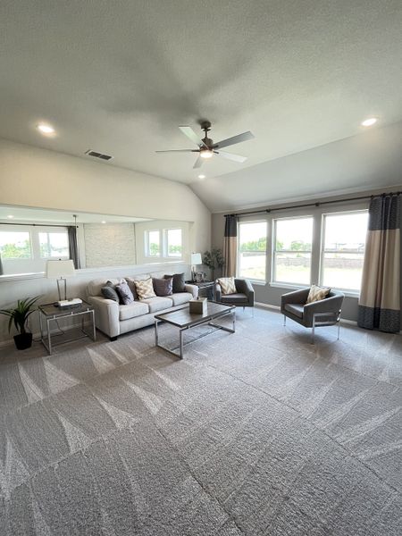 A spacious living room with plush carpet, modern furniture, and ample natural light from large windows.