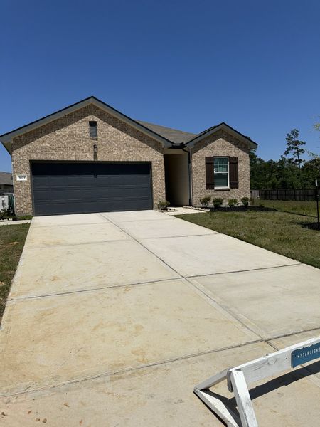 A modern brick home featuring a spacious driveway in Idleloch by Starlight Homes, located in Huffman, TX.
