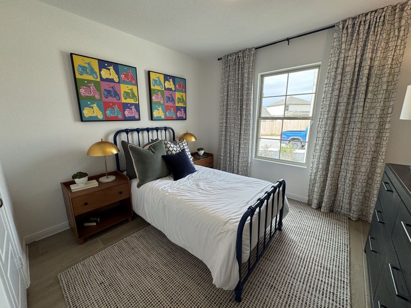 A cozy bedroom featuring colorful scooter art, elegant curtains, and a simple bed with stylish bedding.