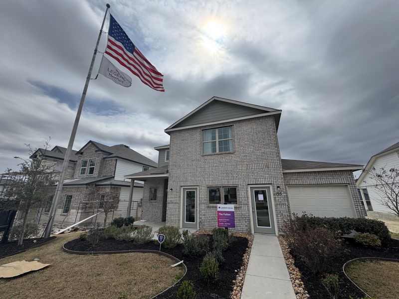 A charming gray brick home with a neatly landscaped yard in Hunters Ranch by Legend Homes (San Antonio, TX).