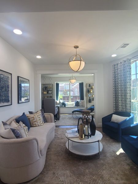 A cozy living room with stylish seating, elegant lighting, and a bright window view, creating a welcoming and comfortable space.