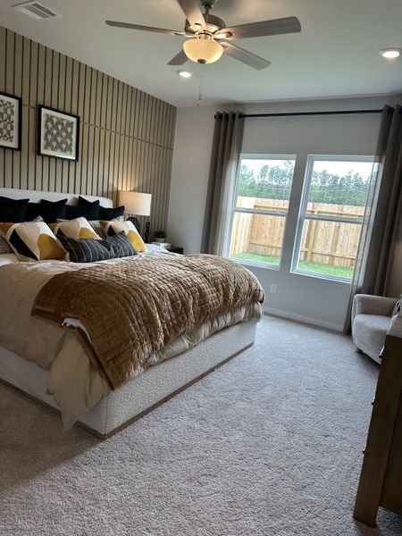 A cozy bedroom featuring accent walls, large windows, and elegant bedding with warm tones.