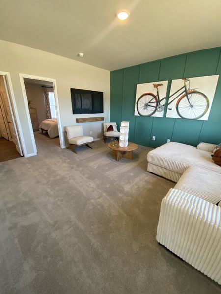 Cozy living area with textured walls, modern TV setup, and chic bicycle artwork for a vibrant touch. Cozy living area with textured walls, modern TV setup, and chic bicycle artwork for a vibrant touch.